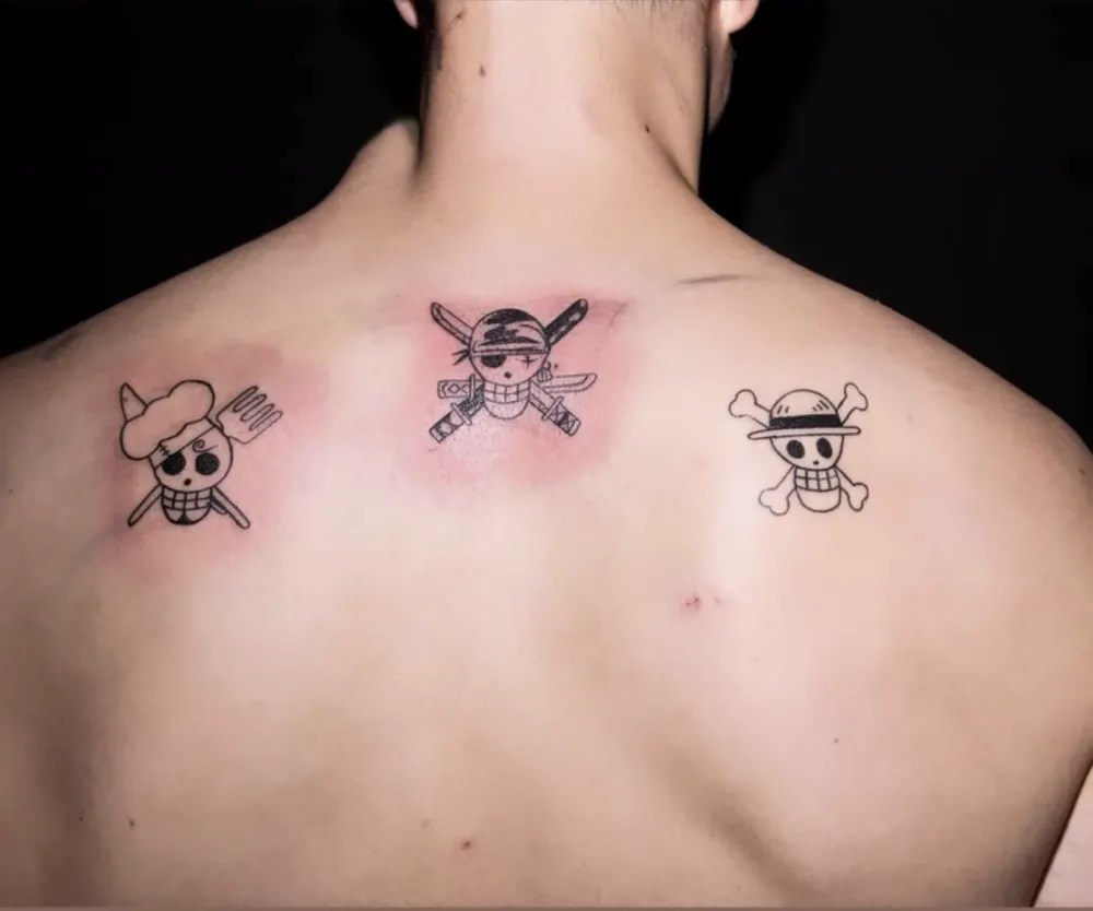 Drei kleine Totenkopf-Tattoos am oberen Rücken